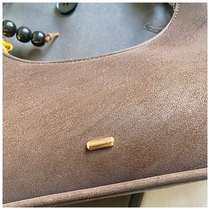 Gros plan du cuir marron à texture litchi avec détails métalliques dorés élégants