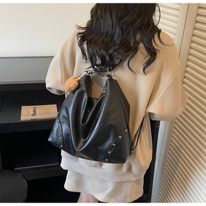 Detail of black faux leather tote with silver rivets and light brown plush charm