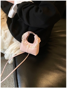 Détail d'un mini sac rose en bandoulière avec bordure en dentelle blanche et logo
