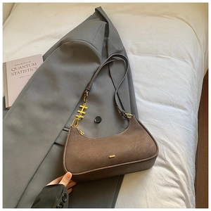 Détail d'un sac demi-lune en daim marron avec des breloques dorées en métal H et D
