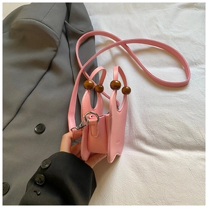 Detailed macro view of pink leather mini bag with decorative brown wooden handle beads