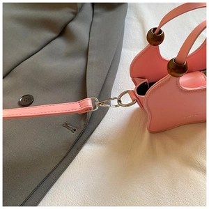 Detail of pink geometric handbag with wooden beads and silver metallic hooks
