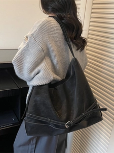 Oversized black faux leather tote bag with decorative buckle straps for casual commuting