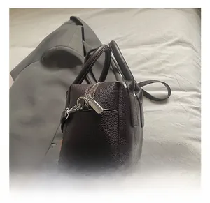 Detail of dark brown lychee grain leather handbag with silver metallic zipper and hardware