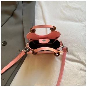 Detail of pink bucket bag with wooden ring handles, magnetic clasp and black lining interior