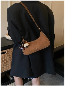 Sac demi-lune rétro en daim marron avec pendentif en bois porté par un mannequin