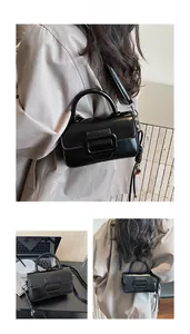 Detail of a vintage black glossy handbag with a large buckle and detachable strap