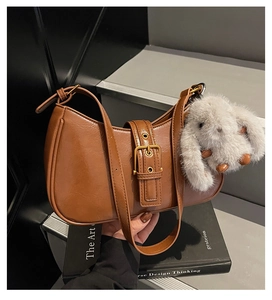 Detail of vintage brown leather underarm bag with brass buckle and rabbit plush charm