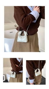 Detail of light green mini crossbody bag with ruffled handle and metallic brand logo