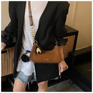 Détails d'un sac hobo en daim marron avec des lettres dorées et des breloques en perles