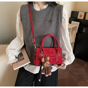 Detail of red suede rectangular crossbody bag with contrast stitching and bear charm
