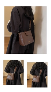 Detail of dark brown leather bucket bag with gold lettering and woven logo strap