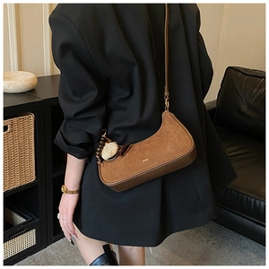 Sac hobo marron en daim avec perles en bois et breloque coquillage porté à l'épaule