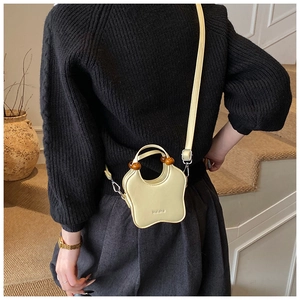 Detail of yellow star-shaped leather handbag featuring wooden beads and metal buckle strap