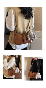 Detail view of brown vintage shoulder bag with a plush bunny charm and smooth leather texture
