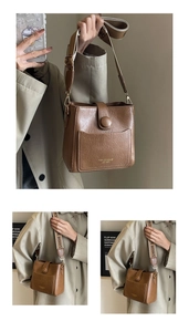 Detail view of brown textured leather bucket bag with wide logo strap and metal buckle