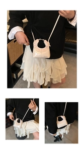 Detail of semi-circular bag showing lace trim and HELAHE logo on cream leather