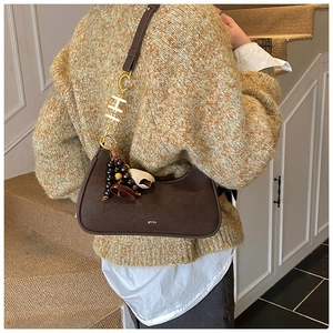 Vue détaillée du sac hobo en daim marron avec pendentif en H doré et accessoire perlé