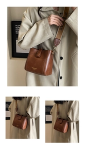 Detail of vintage brown leather bucket bag featuring fashion logo and woven shoulder strap