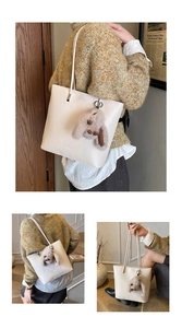 Detail of cream leather bucket bag with litchi texture and cute plush bunny pendant