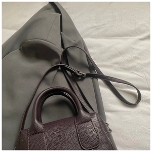 Detail of deep purple lychee pattern leather bag with handles and crossbody strap