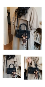 Detail of black leather handbag with white stitching and cute teddy bear charm