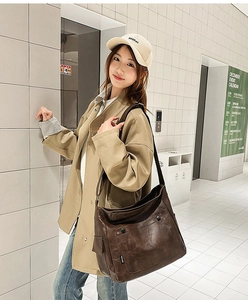 Brown faux leather tote bag shown on a model in a minimalist modern indoor setting