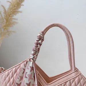 Détail de la poignée du sac matelassé rose avec un élégant foulard en pied-de-poule