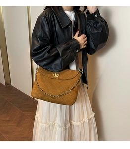 Close-up of brown quilted suede shoulder bag featuring gold chain and ring buckle detail