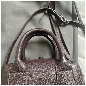 Detail of lychee pattern leather handbag with round handle and silver metal buckle
