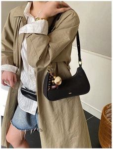 Détail du sac à bandoulière en toile noire avec breloque en perles de bois et zip épuré
