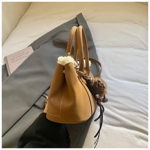 Close-up of caramel suede handbag with white faux fur trim and leopard print charm