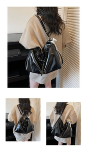 Close-up of black glossy tote bag with silver bow charm and elegant pleated detail