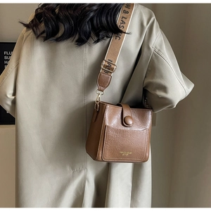 Detail of a brown lychee pattern bucket bag with an embroidered wide shoulder strap