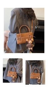 Brown suede handbag featuring a plush bear charm and metallic buckle detail