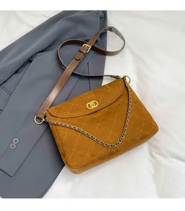 Close-up of brown quilted suede messenger bag with gold clasp and chain strap detail