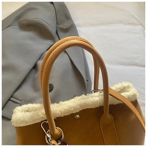 Detail of brown suede bag with white faux fur trim, silver rivets and metal hardware
