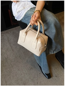 Close-up of cream Boston bag featuring premium lychee texture and dual metal zippers