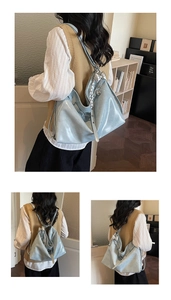 Detail of light blue patent leather tote bag featuring a silver bow charm and woven strap