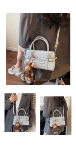 Light blue structured handbag with dual top handles and a brown plush bear charm detail
