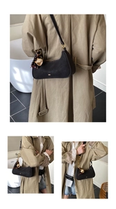 Détail d'un sac hobo noir avec pendentif en perles de bois sur un trench-coat kaki