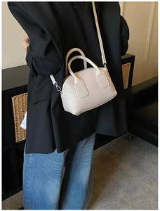 Detail of lychee textured cream crossbody bag with double handles shown on a model
