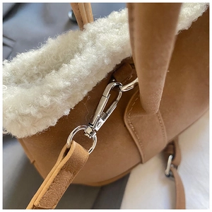 Macro detail of the silver metal hooks and brown suede texture on the crossbody bag