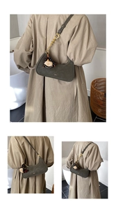 Détail d'un sac hobo en daim vert olive foncé avec breloques rétro et lanière