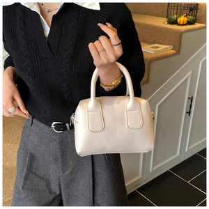 Detail of elegant cream-white lychee texture leather boston bag with metal zipper