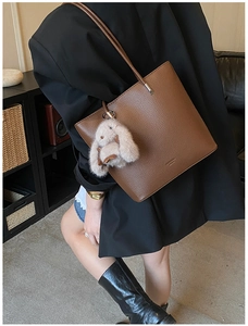Detail of dark brown pebble leather bucket bag with a cute plush rabbit charm