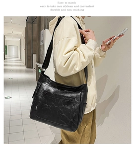 Detail of a black textured leather tote bag with front snap pocket and woven brand label