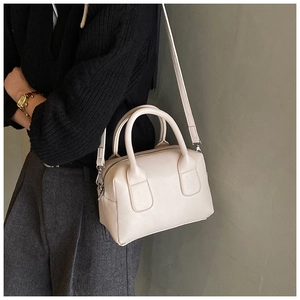 Detail of light beige pebble leather boston bag featuring top handles and shoulder strap