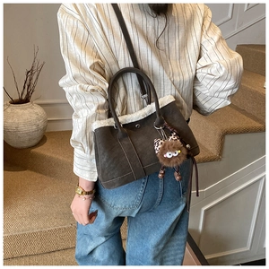 Retro dark brown suede handbag with white faux fur trim and cute plush charm on a model