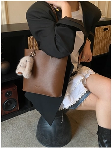 Brown lychee leather tote bag with a pink plush rabbit charm in a daily casual scene